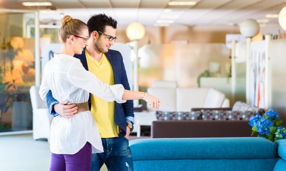 a couple are finger point to the blue sofa