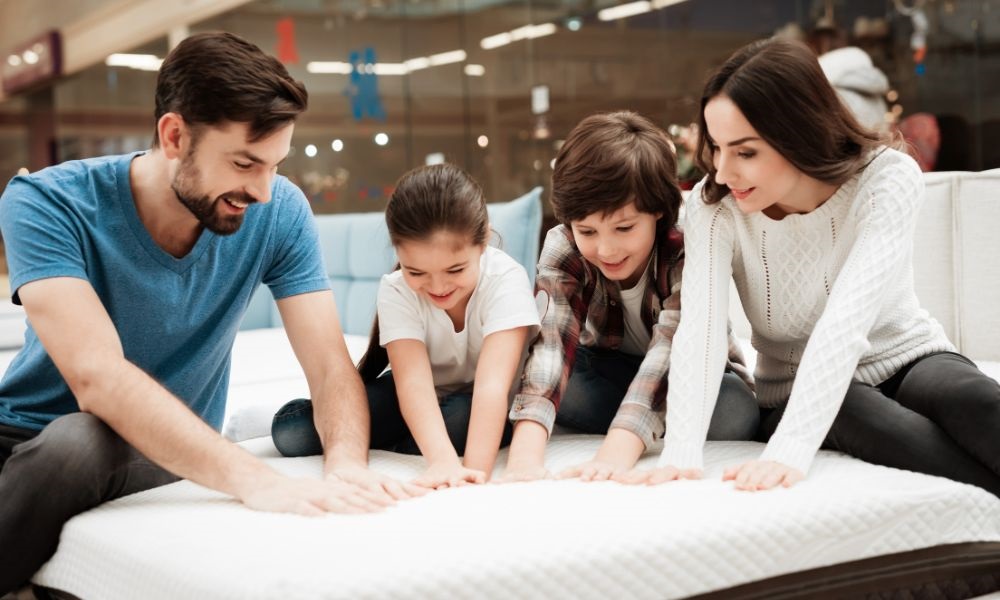 a couple and two children are touching the bed together