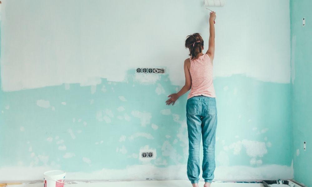 A lady is painting the wall